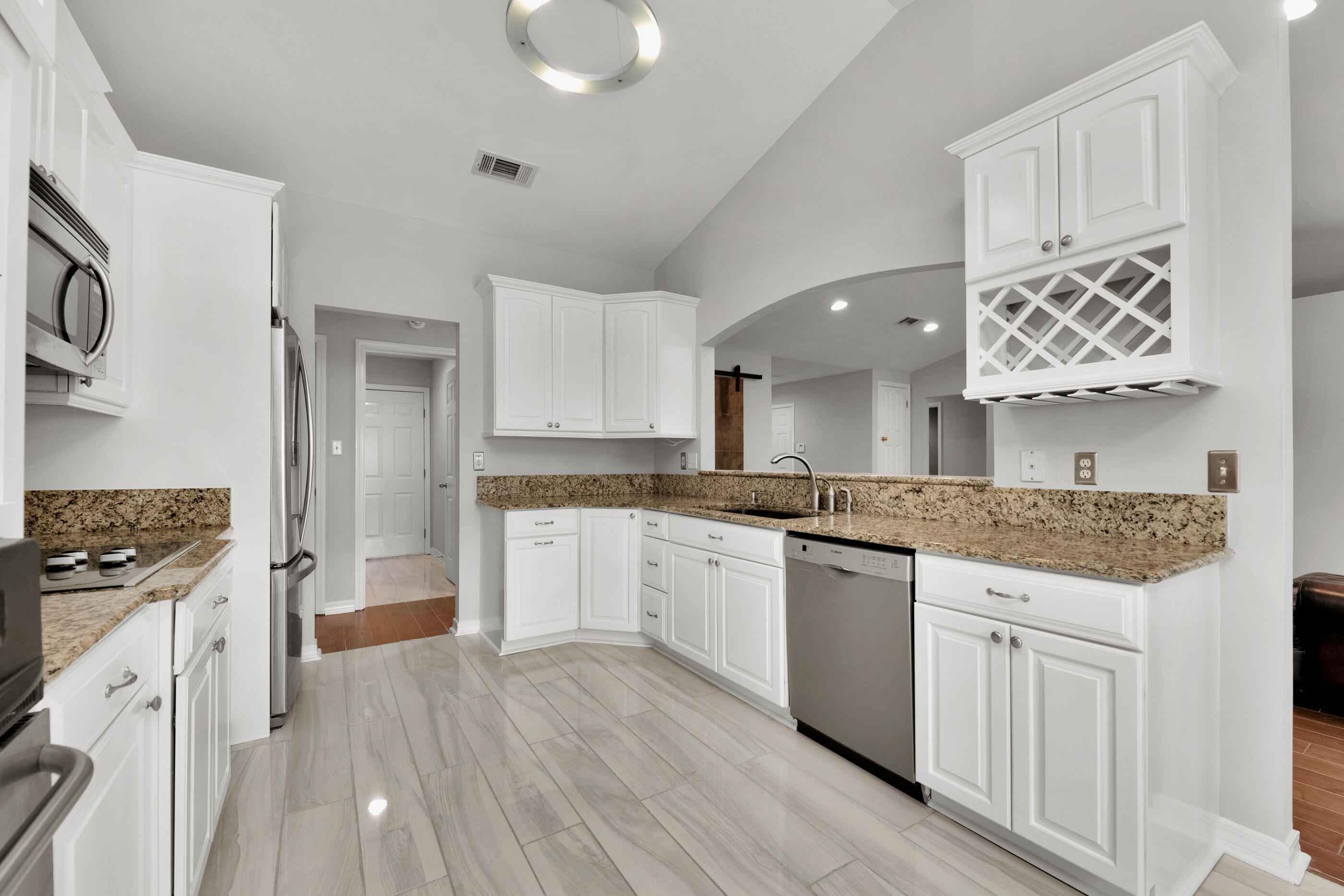 44 Beacon Way Santa Rosa Beach, FL 32459 - Photo 9 of 29 a large kitchen with granite countertop a stove top oven a sink dishwasher and white cabinets with wooden floor
