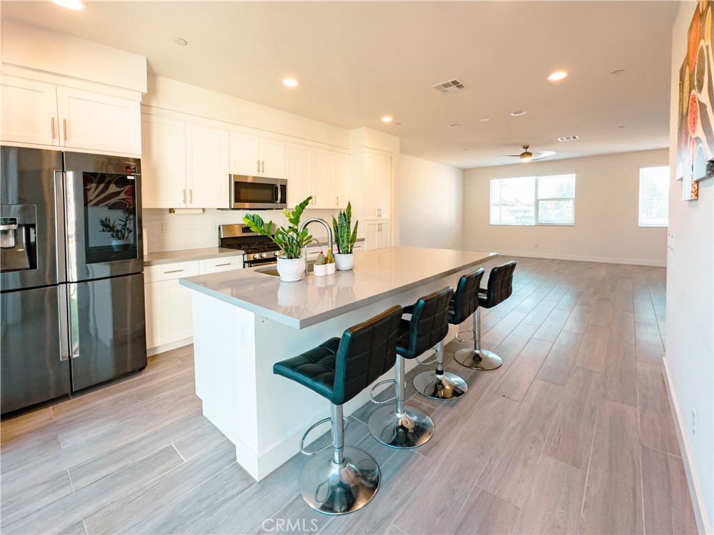 a kitchen with stainless steel appliances a kitchen island hardwood floor sink stove dining table and chairs