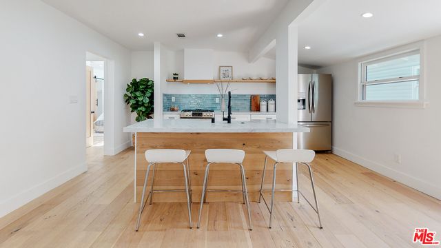 a kitchen with stainless steel appliances granite countertop a refrigerator sink and white cabinets