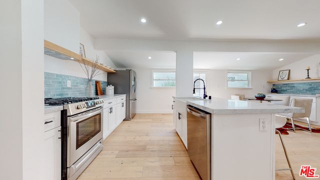 a kitchen with white cabinets stainless steel appliances and potted plant