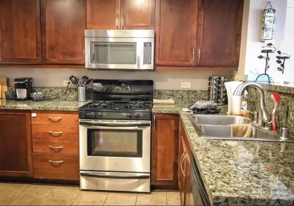 a kitchen with granite countertop a stove top oven microwave and cabinets