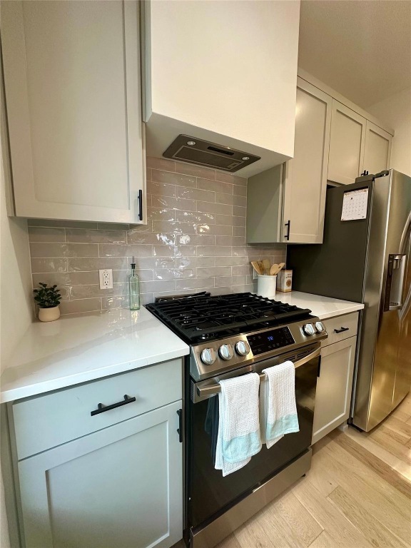 3417 Elija Street, Unit 2 Austin, TX 78745 - Photo 20 of 28 Kitchen with stainless steel appliances, wall chimney exhaust hood, light wood-style flooring, gray cabinets, and light stone countertops
