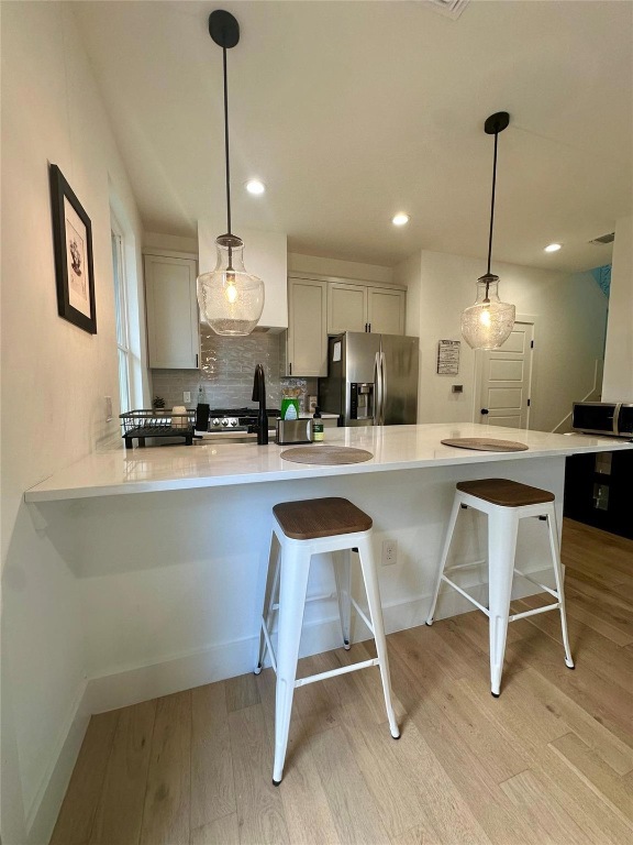 3417 Elija Street, Unit 2 Austin, TX 78745 - Photo 24 of 28 Kitchen featuring a peninsula, pendant lighting, a breakfast bar area, stainless steel appliances, and light stone countertops