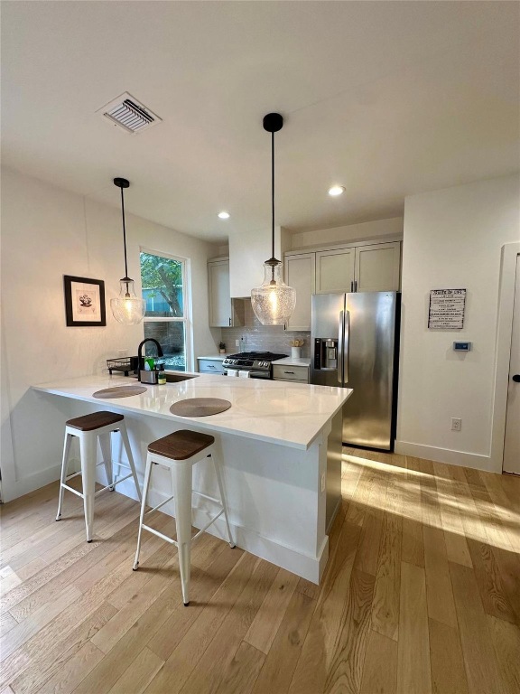 3417 Elija Street, Unit 2 Austin, TX 78745 - Photo 25 of 28 Kitchen featuring a breakfast bar area, stainless steel appliances, hanging light fixtures, light stone counters, and recessed lighting
