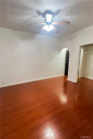 a view of an empty room with window and wooden floor