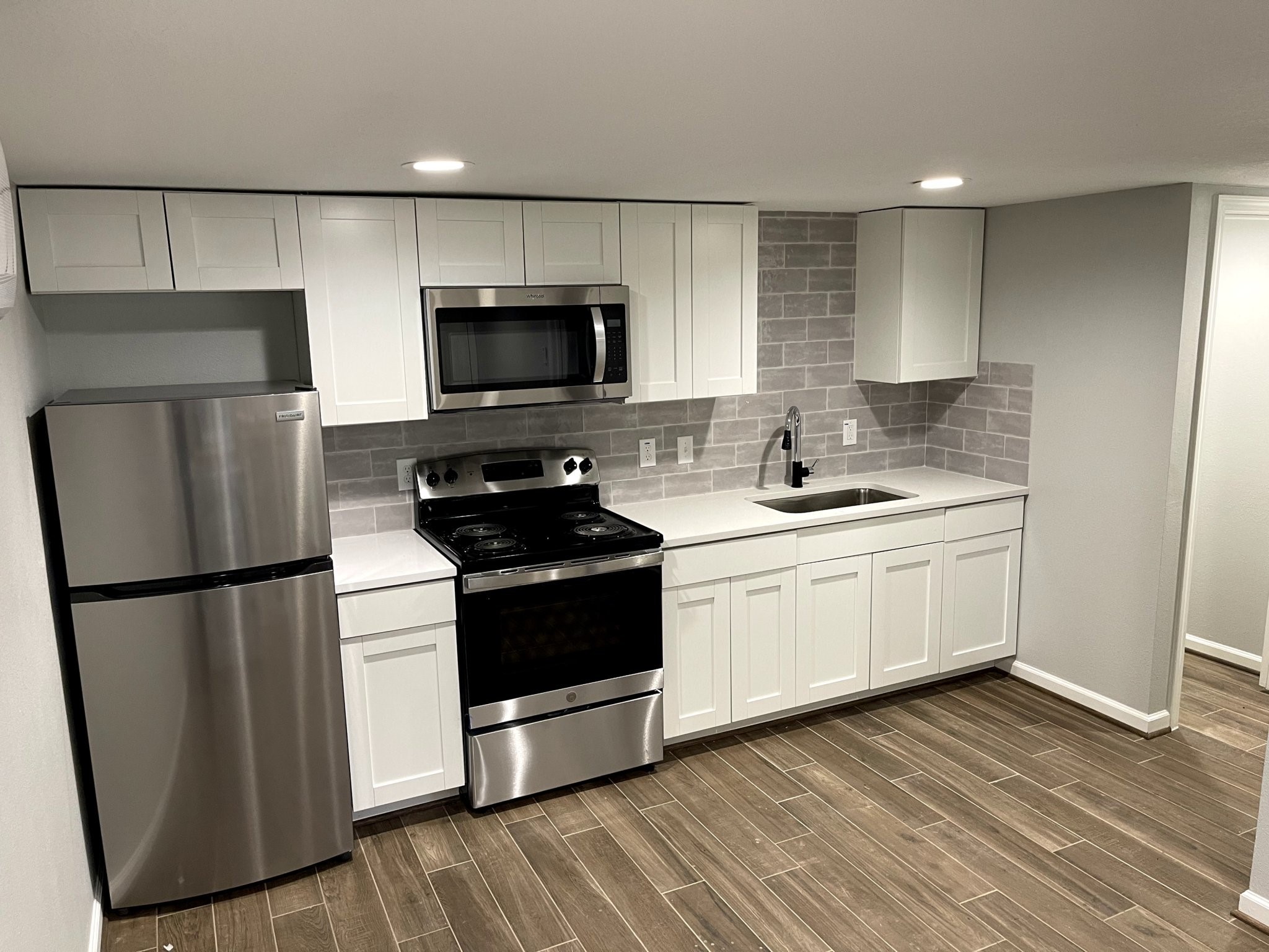 a kitchen with a sink a refrigerator a microwave and cabinets