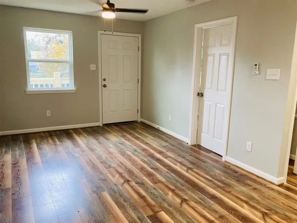 a view of an empty room with wooden floor and a window