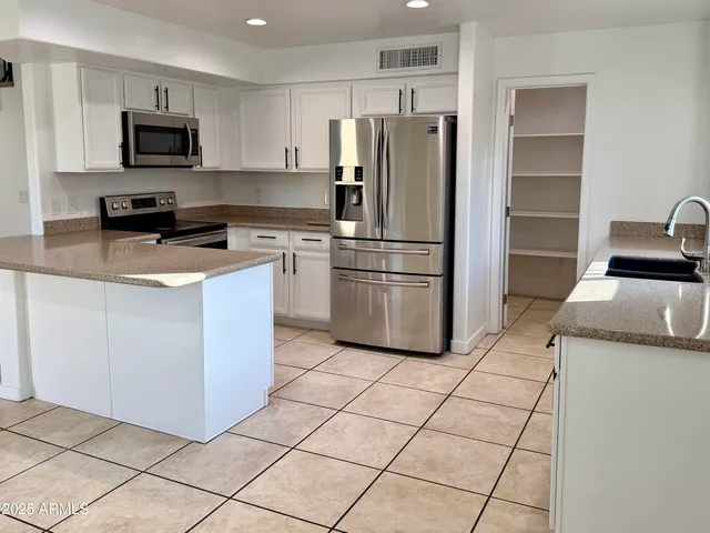 a kitchen with stainless steel appliances granite countertop a refrigerator stove a sink and a microwave