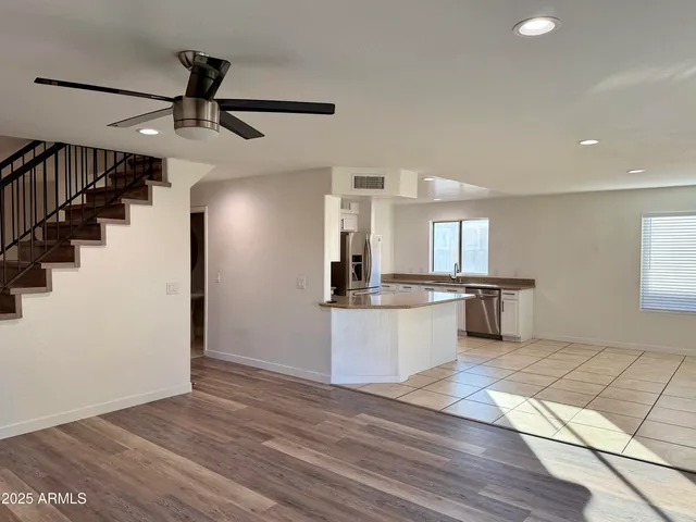 a view of kitchen and empty room with wooden floor