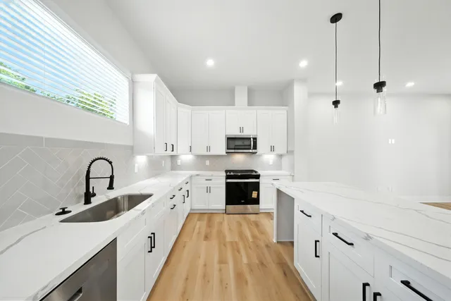 a kitchen with a sink a stove a refrigerator and white cabinets
