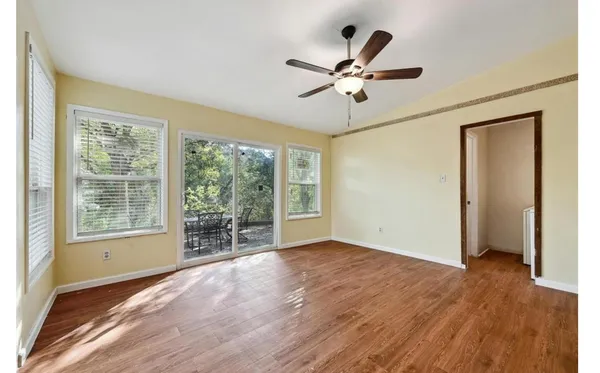 a view of empty room with wooden floor and fan