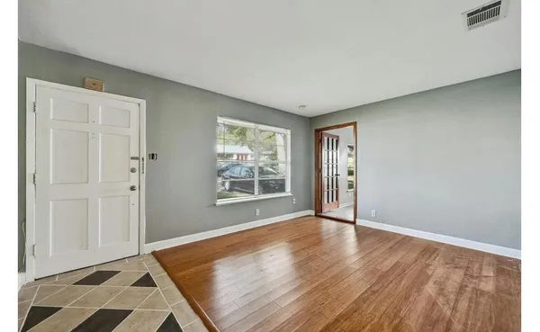 a view of an empty room with wooden floor and a window