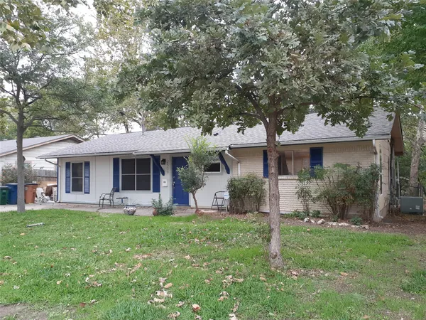 a front view of house with a garden and trees