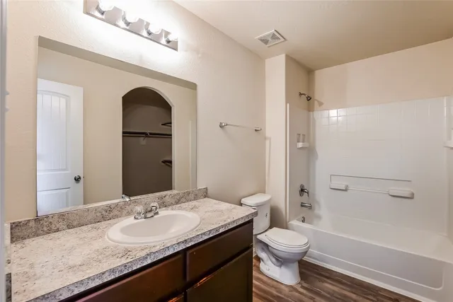 a bathroom with a granite countertop toilet a sink and a mirror
