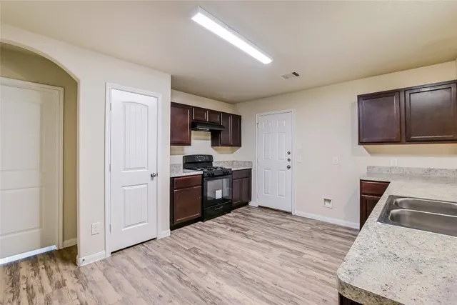a kitchen with a refrigerator stove and wooden floor