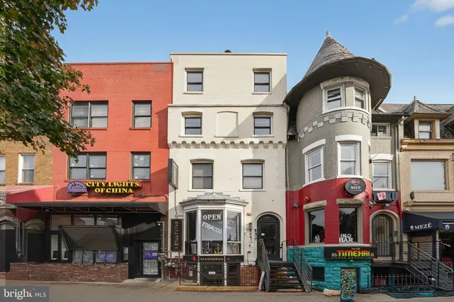 a front view of multi story residential apartment building with retail shops