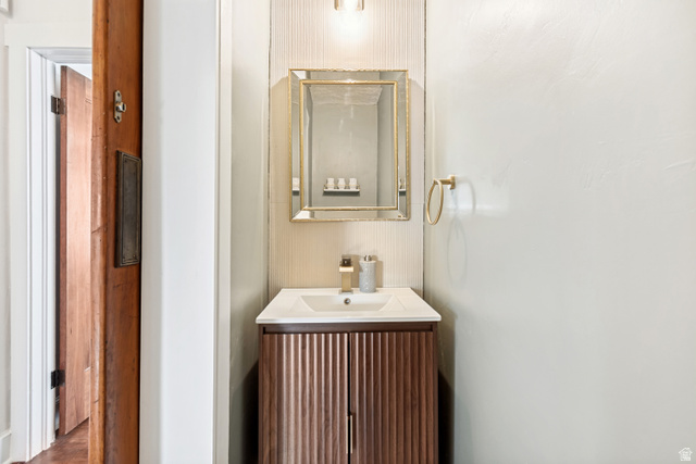 4883 South Center Street Murray, UT 84107 - Photo 14 of 32 Half Bath. Modern vanity with a fluted wood-finish cabinet, integrated white sink, and gold-toned faucet