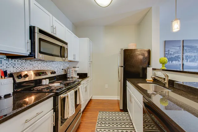 a kitchen with stainless steel appliances granite countertop a sink a stove and a wooden floors