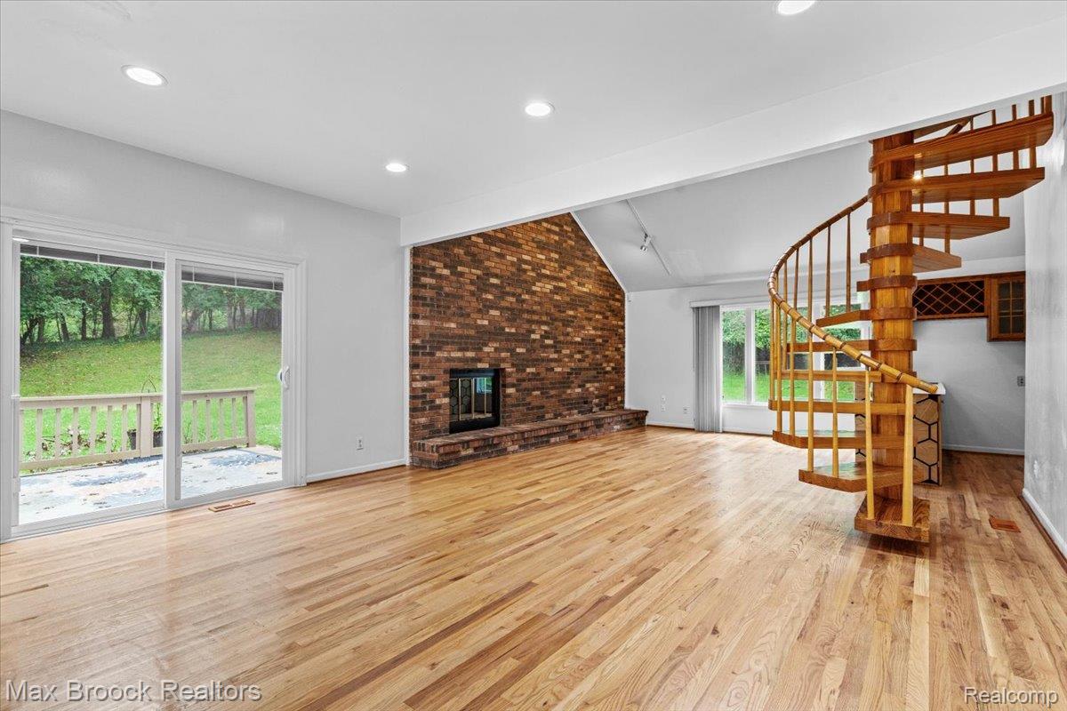 1830 Lone Pine Road Bloomfield Hills, MI 48302 - Photo 23 of 70 Expansive room featuring wood-finish flooring, a brick fireplace, and a spiral staircase with a wet bar and door wall to large deck.
