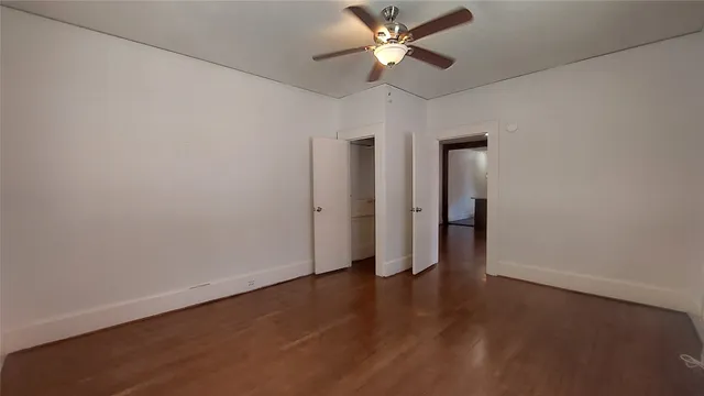 an empty room with wooden floor and fan