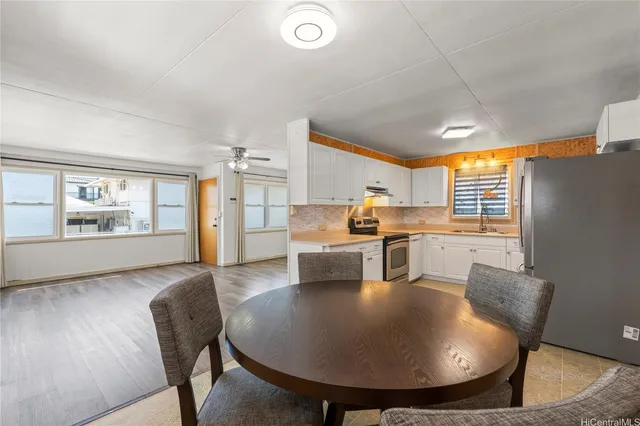 a living room with stainless steel appliances furniture a dining table and kitchen view