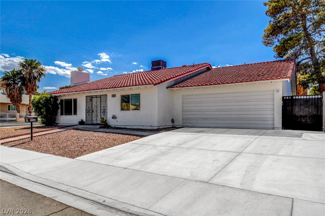 A terracotta-tiled roof crowns this residence, featuring a secure gated entry and an attached garage.