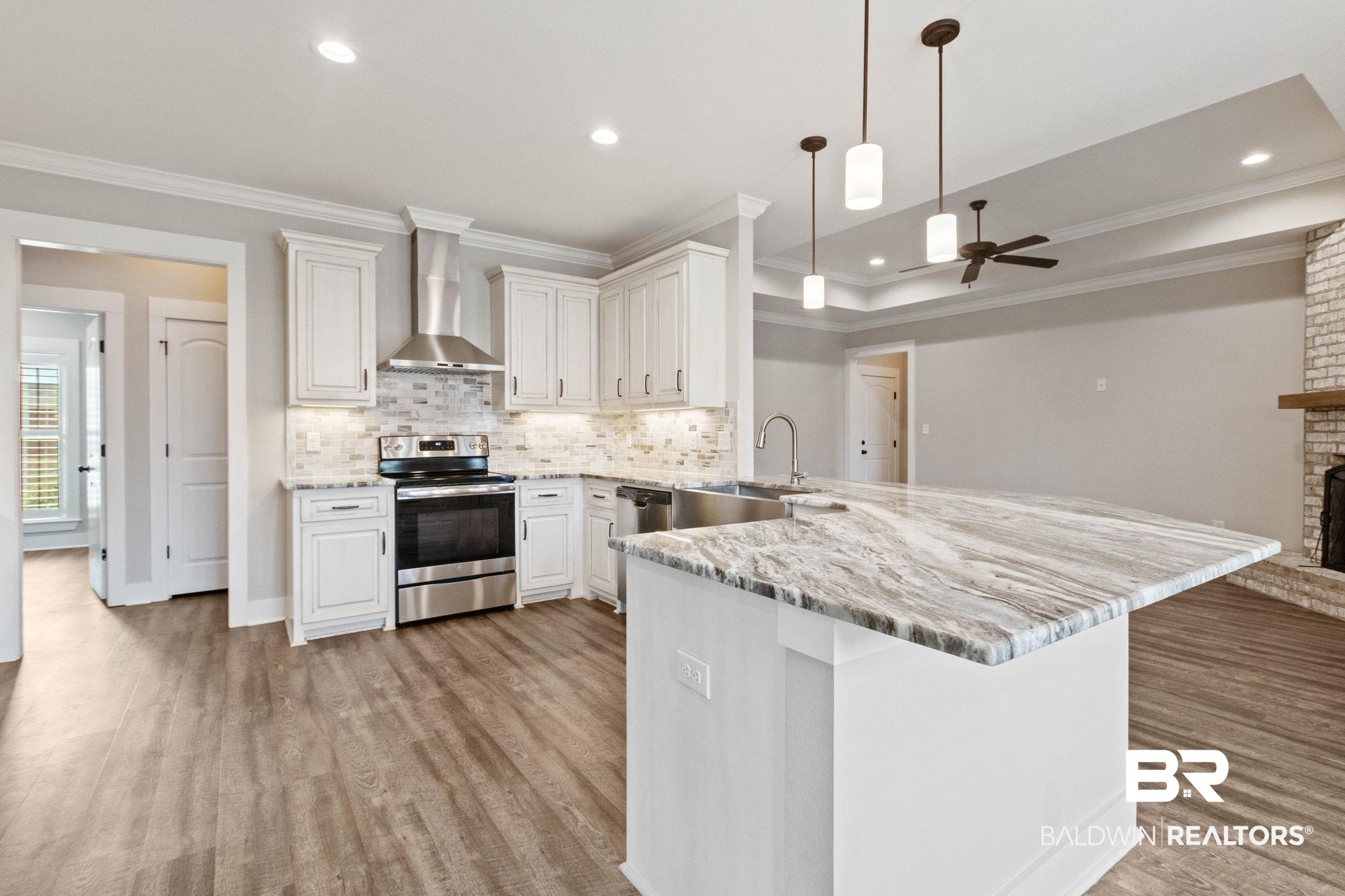 17376 Bankhead Boulevard Fairhope, AL 36532 - Photo 21 of 73 Kitchen with a peninsula, stainless steel appliances, decorative light fixtures, crown molding, and light stone countertops