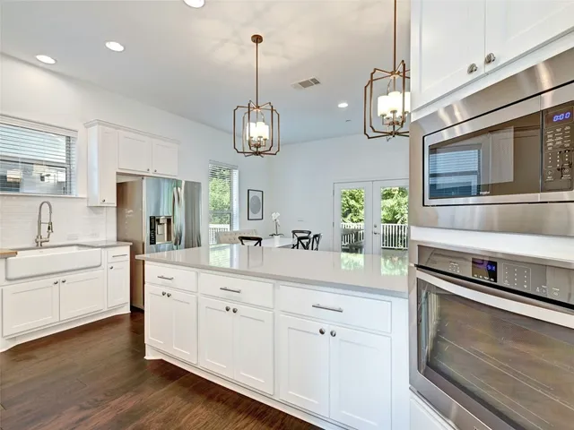 a kitchen with a sink stainless steel appliances and wooden floor