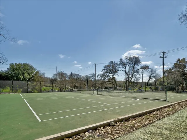 a view of a tennis ground with large trees