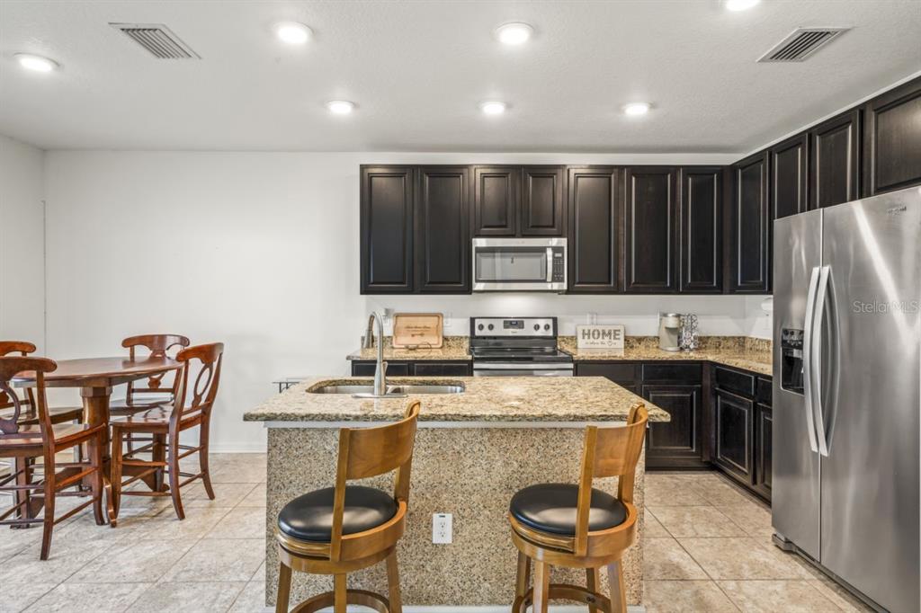 571 Old Windsor Way Spring Hill, FL 34609 - Photo 16 of 61 a kitchen with stainless steel appliances granite countertop a stove a sink a microwave a refrigerator and chairs
