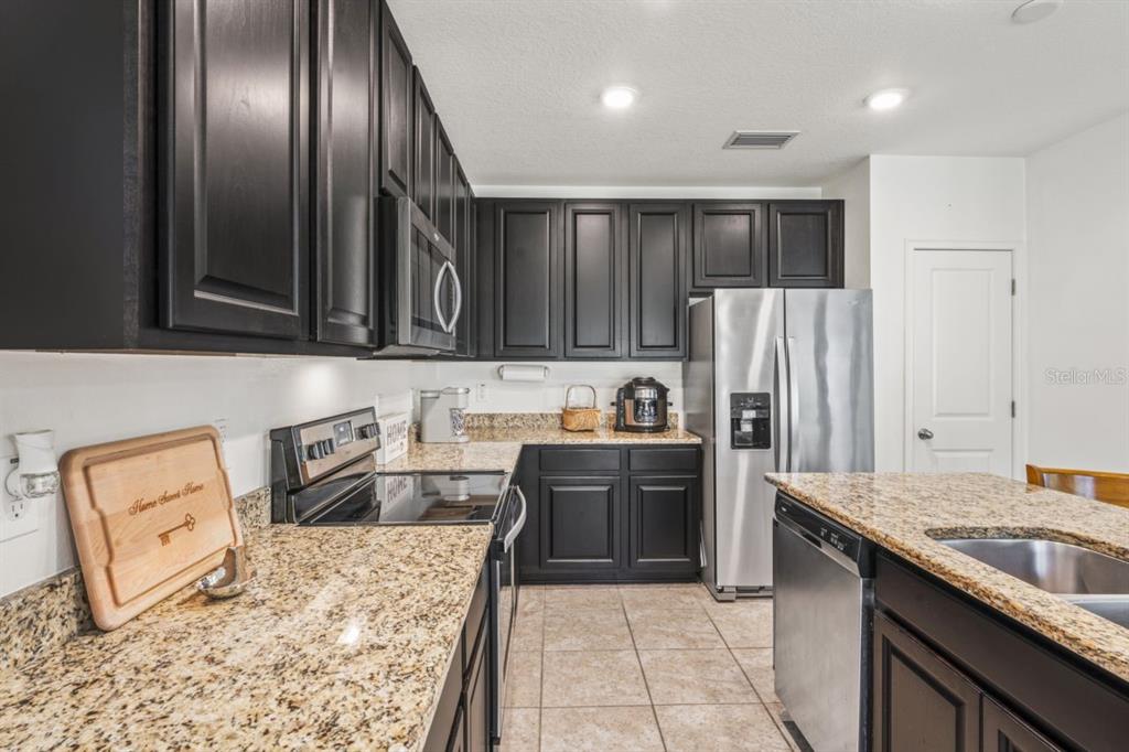 571 Old Windsor Way Spring Hill, FL 34609 - Photo 18 of 61 a kitchen with granite countertop stainless steel appliances and wooden cabinets