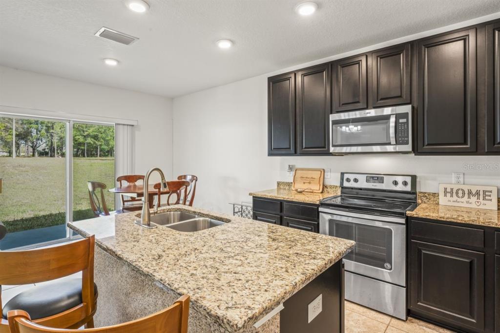571 Old Windsor Way Spring Hill, FL 34609 - Photo 18 of 61 a kitchen with stainless steel appliances granite countertop a stove top oven microwave and refrigerator