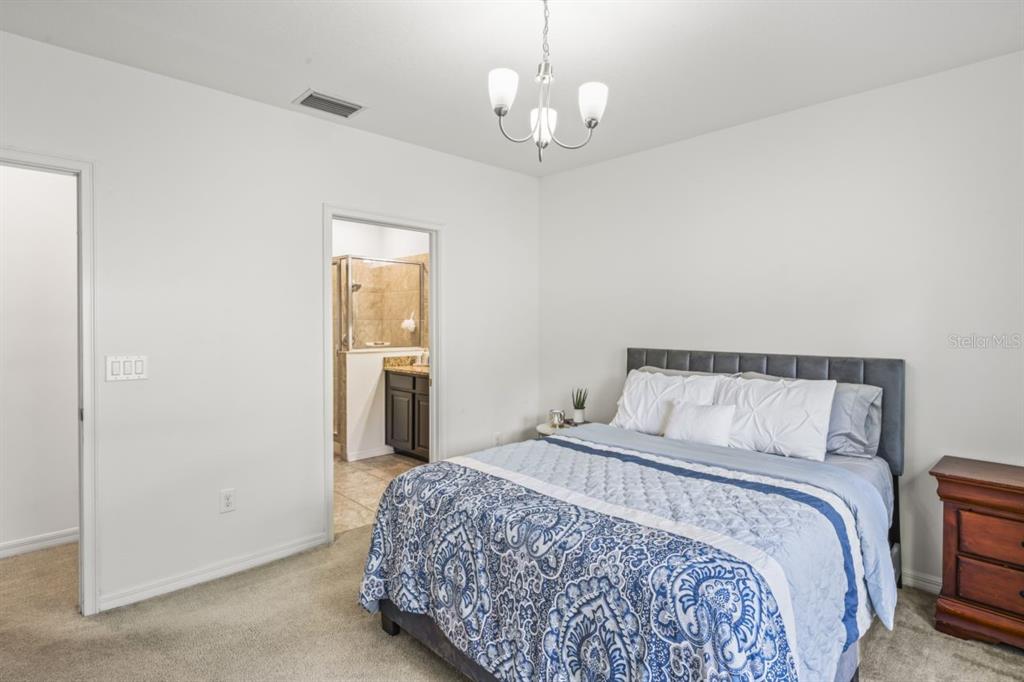 571 Old Windsor Way Spring Hill, FL 34609 - Photo 23 of 61 a bedroom with a large bed and chandelier