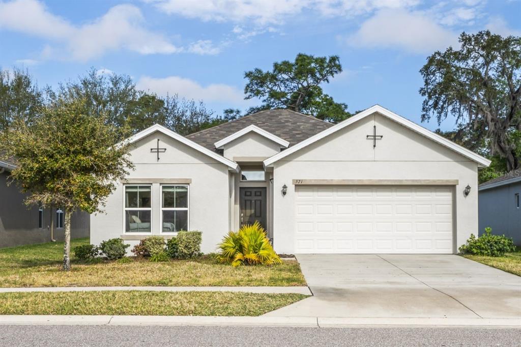 571 Old Windsor Way Spring Hill, FL 34609 - Photo 59 of 61 a view of a white house with a yard and plants