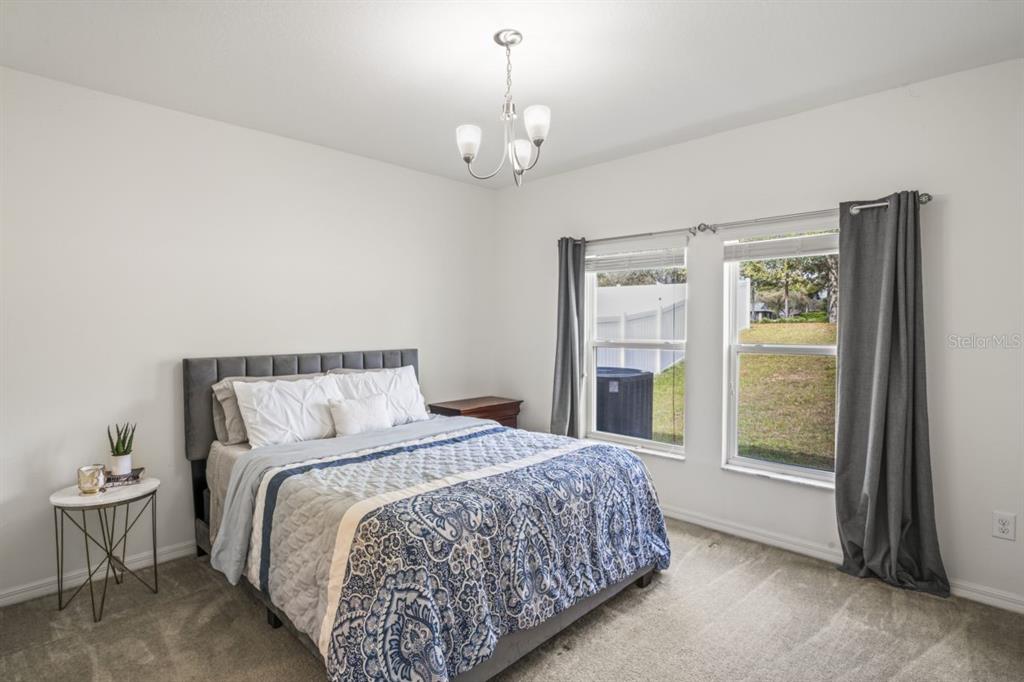 571 Old Windsor Way Spring Hill, FL 34609 - Photo 7 of 61 a spacious bedroom with a balcony a bed and a chandelier