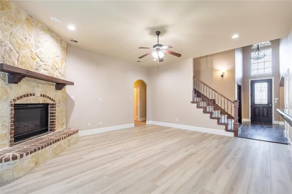 a view of an empty room with wooden floor and a fireplace