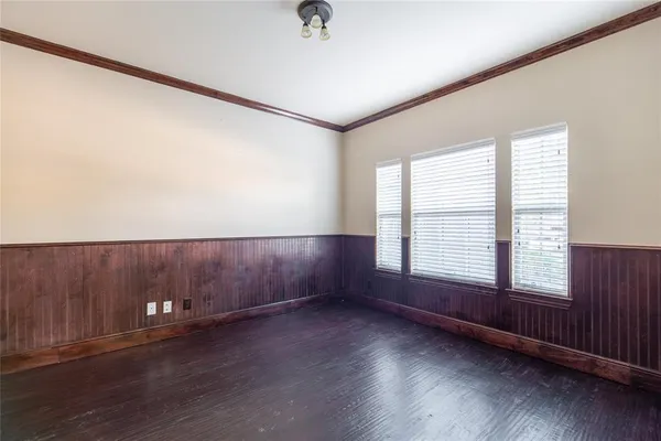 an empty room with wooden floor and windows with curtains