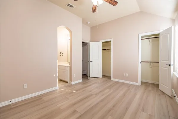 an empty room with wooden floor and a ceiling fan