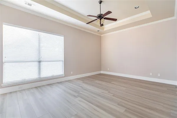 an empty room with wooden floor ceiling fan and windows