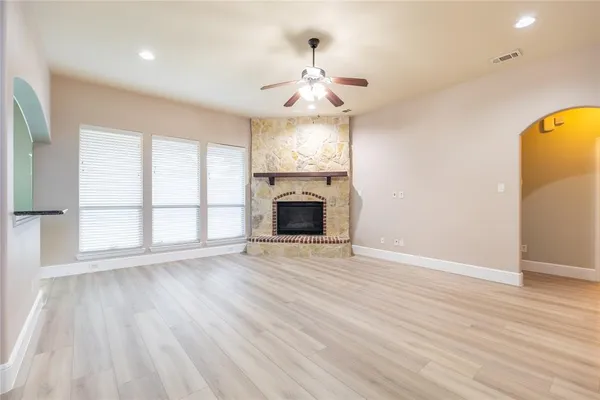 an empty room with wooden floor fireplace and windows