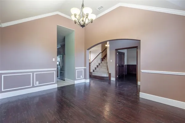a view of a livingroom with wooden floor staircase and a kitchen space