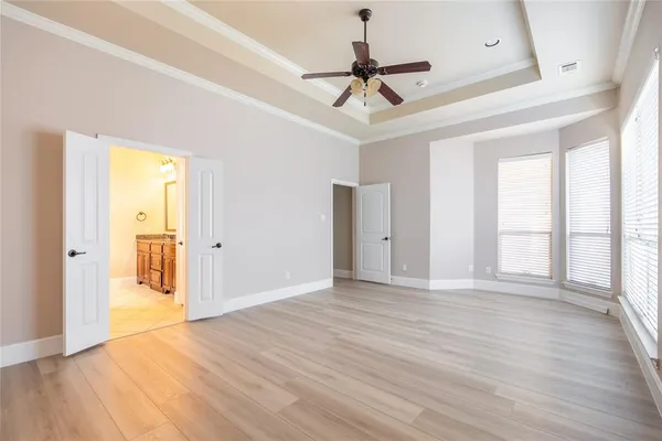 a view of an empty room with wooden floor and a ceiling fan
