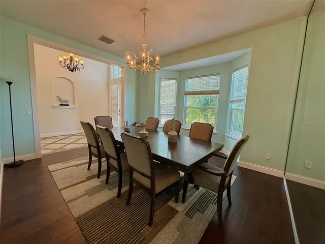 a view of a dining room with furniture a chandelier and wooden floor