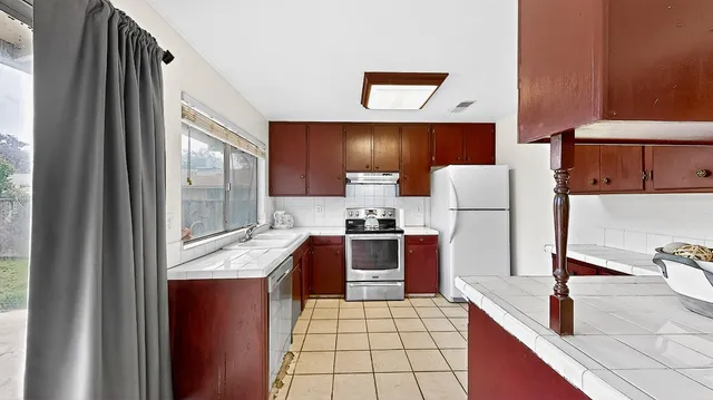a kitchen with granite countertop a sink a stove and a refrigerator