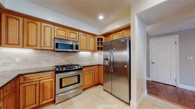 a kitchen with stainless steel appliances granite countertop a refrigerator a stove and a sink