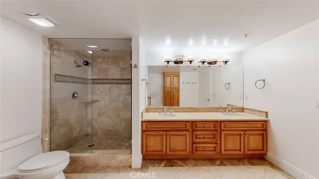 a bathroom with a granite countertop sink a toilet a mirror and shower