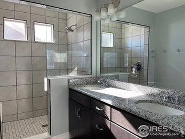 a bathroom with a granite countertop sink a mirror and shower