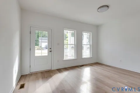 an empty room with wooden floor and windows