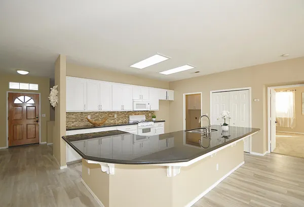 a view of kitchen with granite countertop lots of counter top space and living room