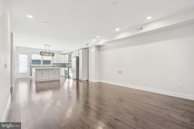 a view of kitchen with refrigerator stove and wooden floor